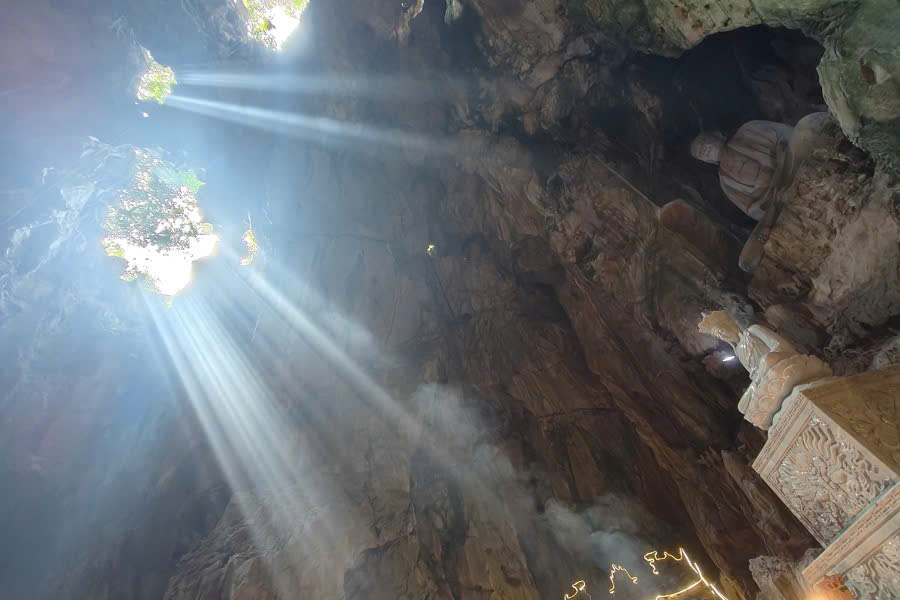 Natural sunlight illuminating Buddhist shrines inside Huyen Khong Cave at Marble Mountains