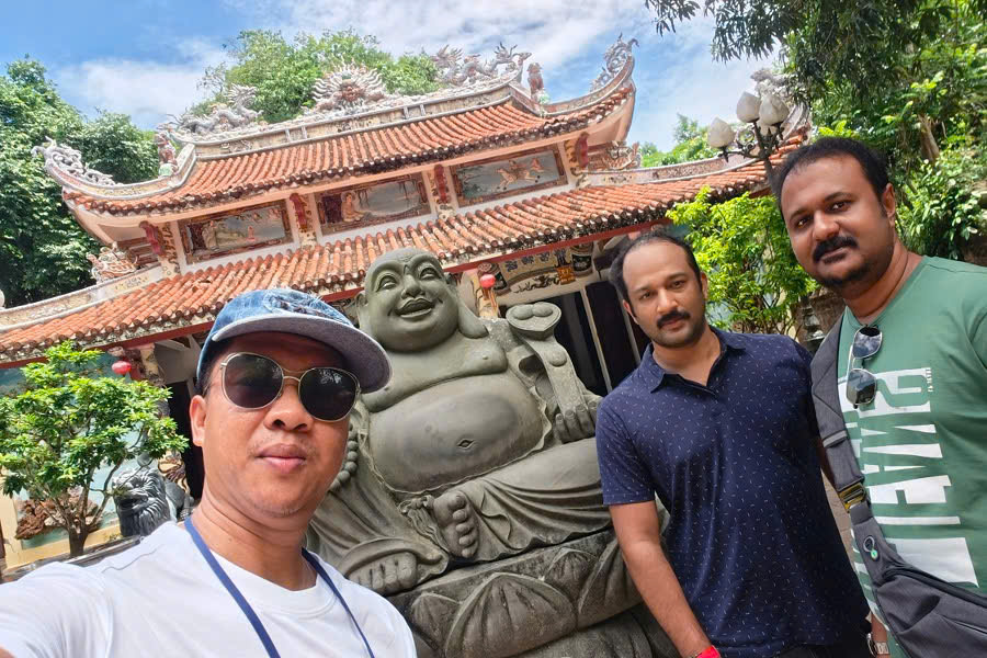 Mr. Viet Nguyen with guests at the Happy Buddha statue in Tam Thai Temple, Marble Mountains, during a 10-Day Central Vietnam Package Tour