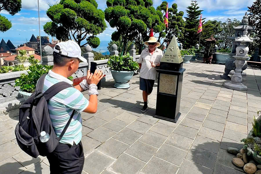Viet Nguyen takes a photo for a guest beside the Ba Na Hills Peak sign