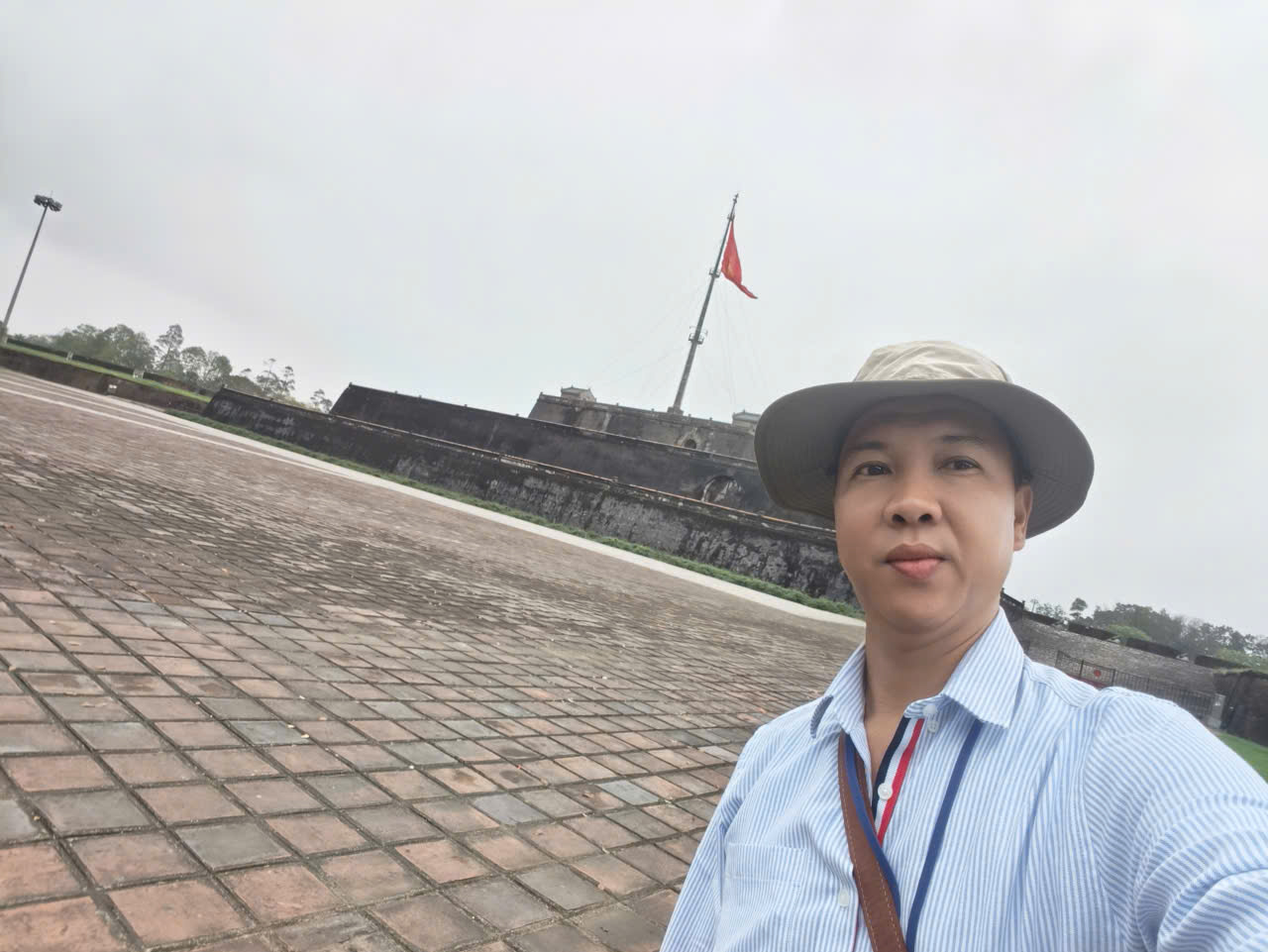 Viet Nguyen posing in front of the Flag Tower at Hue Imperial City, Vietnam.