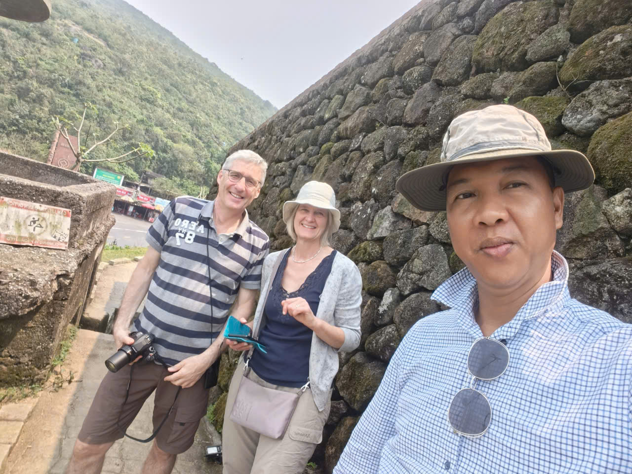 Viet Nguyen taking a photo with a couple at the summit of Hai Van Pass overlooking the coast of Central Vietnam.