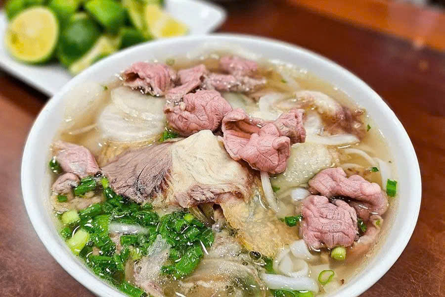 Bowl of Vietnamese beef pho noodle soup with sliced beef, rice noodles, fresh herbs and broth